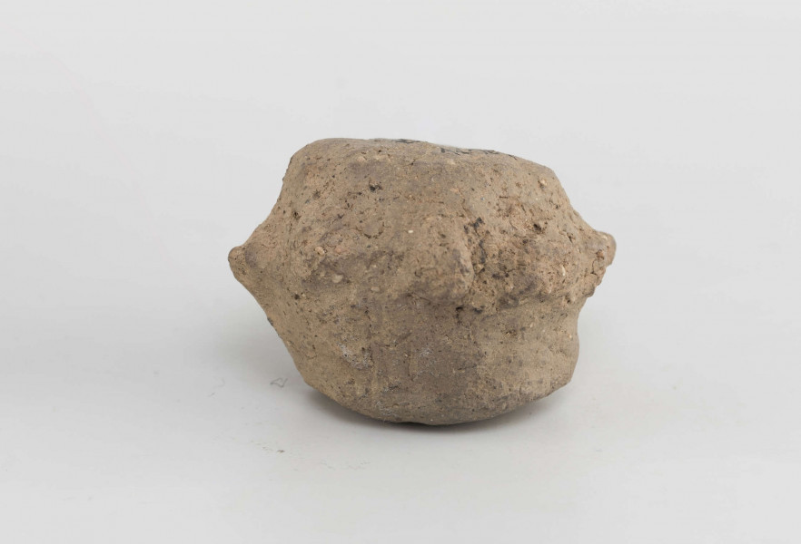 Grzechotka gliniana. Kształt zbliżony do walcowatego. W połowie wysokości ozdobiona 9 guzkami.