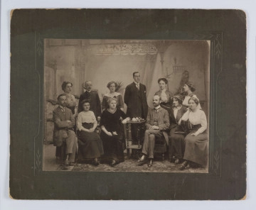 ML/H/F/267 ML/H/F/267 - Fotografia wykonana w atelier na tle panelu z kotarą, na podłodze dywan. Do zdjęcia pozuje 12 osób: 8 kobiet i 4 mężczyzn. Od lewej siedzi Władysław Kunicki, przy stoliku Romana Zapasiewicz, za stolikiem Tołwiński, obok z prawej Józefa Kunicka, z lewej Rennard.
Fotografia naklejona na tekturę w odcieniu szarej zieleni.
Na odwrociu nazwiska niektórych osób wypisane ołówkiem.