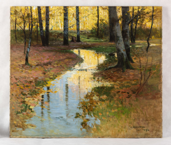 Pejzaż jesienny z krętą, wijącą się strugą na pierwszym planie. Ukazany wycinek lasu. Po obu stronach wody na barwnym, różowo-żółtym poszyciu szaro-czarne pnie drzew. Na drugim planie drzewa pokryte żółtymi liśćmi oświetlonymi jasnym blaskiem słonecznym. 