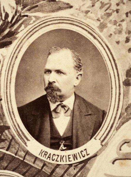 Fotografie w odcieniu sepii umieszczone na tle drzew i roślin, w centralnym miejscu postać kobiety ze sztandarem i aniołkami, wkomponowane widoki budowanej stacji, mostu kolejowego i lokomotywy. Największe zdjęcie w górnej, środkowej części bez podpisu, prawdopodobnie inż. głównej kolei nadwiślańskiej Tadeusz Chrzanowski lub jego następca Walery Titkow. Wśród podobizn pracownicy Biura Głównego Inżyniera: inż. Włodzimierz Stanisławski - pomocnik głównego inżyniera; inż. Feliks Kucharzewski -  pomocnik naczelnika biura; Feliks Kamocki - naczelnik kancelarii; Witold Lanci - naczelnik Wydz. Architektury; dr Wacław Lasocki- służba zdrowia; Władysław Radwan - sprawy zakupu gruntów; inż. Stanisław hr Scipio - projektant mostów kolejowych i jego współpracownicy: inż. Stefan Zieliński, inż. Maurycy Machalski, inż. Feliks Kucharzewski. Fotografia w passe - partout, za szkłem, oprawiona w drewnianą, profilowaną ramę.