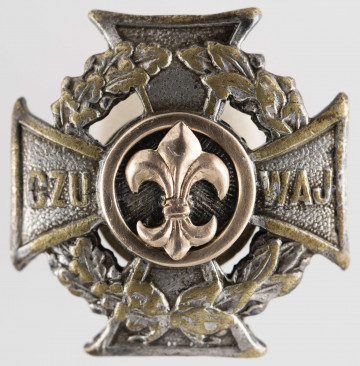 ML/MART/284 - Krzyż harcerski ze złotą lilijką wykonany z metalu, należał do harcerza Stanisława Maciąga. Z tyłu krzyż na zapięcie/nakrętkę. Krzyż harcerski 4-ramienny wykonany z metalu, na środku złota lilijka harcerska w tle liście wawrzynu, na krzyżu napis 