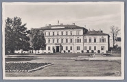 ML/H/320 - Pocztówka czarnobiała z widokiem na plac Litewski (Adolf Hitler Platz) w Lublinie w czasie okupacji hitlerowskiej. Na awersie od frontu dawny Pałac Rządu Gubernialnego. Główny korpus gmachu trzykondygnacyjny. Boczne skrzydła dwukondygnacyjne. Z lewej strony budynek zasłonięty drzewami. Na dachu zatknięta flaga. Na pierwszym planie trawniki i rabaty. Fotografia otoczona białym tłem. W p.d. rogu w owalu nazwa wydawnictwa „Stengel” naniesiona drukiem. Stylizowane na odręczne pismo litery w kolorze białym. Krawędzie karty nieregularne. Na rewersie w l.g. rogu tytuł pocztówki. U góry, pośrodku, powtórzone logo wydawnictwa. Pod nim pełna nazwa i adres wydawcy oddzielające pole na korespondencje od pola na adres. W l.d. rogu informacja o lubelskiej księgarni Karla J. Ludwiga kolportującej pocztówki. Napisy w języku niemieckim. W p.d. rogu nr wydawniczy serii (?). Napisy i linatura w kolorze czarnym. Brak śladów obiegu pocztowego. 