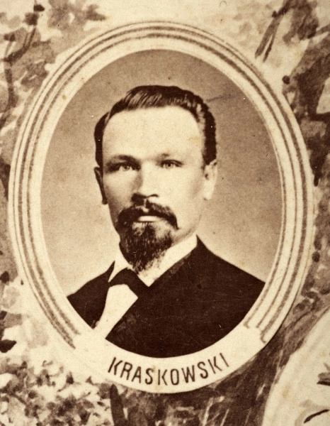 Fotografie w odcieniu sepii umieszczone na tle drzew i roślin, w centralnym miejscu postać kobiety ze sztandarem i aniołkami, wkomponowane widoki budowanej stacji, mostu kolejowego i lokomotywy. Największe zdjęcie w górnej, środkowej części bez podpisu, prawdopodobnie inż. głównej kolei nadwiślańskiej Tadeusz Chrzanowski lub jego następca Walery Titkow. Wśród podobizn pracownicy Biura Głównego Inżyniera: inż. Włodzimierz Stanisławski - pomocnik głównego inżyniera; inż. Feliks Kucharzewski -  pomocnik naczelnika biura; Feliks Kamocki - naczelnik kancelarii; Witold Lanci - naczelnik Wydz. Architektury; dr Wacław Lasocki- służba zdrowia; Władysław Radwan - sprawy zakupu gruntów; inż. Stanisław hr Scipio - projektant mostów kolejowych i jego współpracownicy: inż. Stefan Zieliński, inż. Maurycy Machalski, inż. Feliks Kucharzewski. Fotografia w passe - partout, za szkłem, oprawiona w drewnianą, profilowaną ramę.