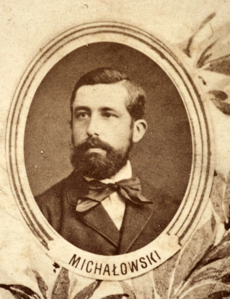 Fotografie w odcieniu sepii umieszczone na tle drzew i roślin, w centralnym miejscu postać kobiety ze sztandarem i aniołkami, wkomponowane widoki budowanej stacji, mostu kolejowego i lokomotywy. Największe zdjęcie w górnej, środkowej części bez podpisu, prawdopodobnie inż. głównej kolei nadwiślańskiej Tadeusz Chrzanowski lub jego następca Walery Titkow. Wśród podobizn pracownicy Biura Głównego Inżyniera: inż. Włodzimierz Stanisławski - pomocnik głównego inżyniera; inż. Feliks Kucharzewski -  pomocnik naczelnika biura; Feliks Kamocki - naczelnik kancelarii; Witold Lanci - naczelnik Wydz. Architektury; dr Wacław Lasocki- służba zdrowia; Władysław Radwan - sprawy zakupu gruntów; inż. Stanisław hr Scipio - projektant mostów kolejowych i jego współpracownicy: inż. Stefan Zieliński, inż. Maurycy Machalski, inż. Feliks Kucharzewski. Fotografia w passe - partout, za szkłem, oprawiona w drewnianą, profilowaną ramę.