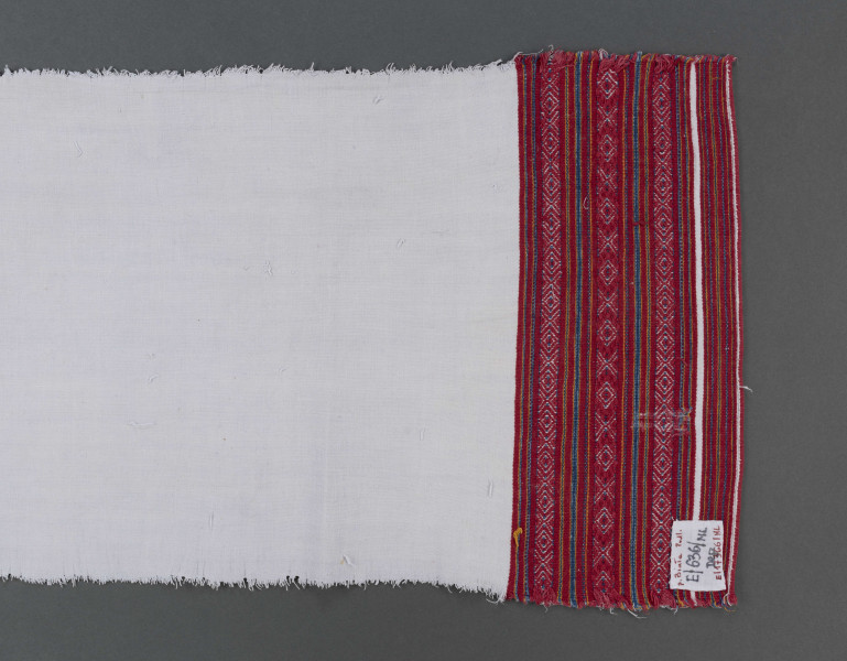 Ręcznik z samodziałowego płótna tkanego splotem prostym. Brzegi dolne, na szer. 14,5 cm, ozdobione ornamentem tkackim zw. pereborami. Ułożony pasowo, złożone z motywów geometrycznych w postaci rombów, kształtów litery X oraz drobnych prążków, w kolorze niebieskim, pomarańczowym i czerwonym.