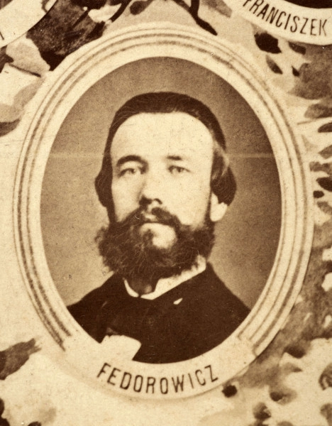 Fotografie w odcieniu sepii umieszczone na tle drzew i roślin, w centralnym miejscu postać kobiety ze sztandarem i aniołkami, wkomponowane widoki budowanej stacji, mostu kolejowego i lokomotywy. Największe zdjęcie w górnej, środkowej części bez podpisu, prawdopodobnie inż. głównej kolei nadwiślańskiej Tadeusz Chrzanowski lub jego następca Walery Titkow. Wśród podobizn pracownicy Biura Głównego Inżyniera: inż. Włodzimierz Stanisławski - pomocnik głównego inżyniera; inż. Feliks Kucharzewski -  pomocnik naczelnika biura; Feliks Kamocki - naczelnik kancelarii; Witold Lanci - naczelnik Wydz. Architektury; dr Wacław Lasocki- służba zdrowia; Władysław Radwan - sprawy zakupu gruntów; inż. Stanisław hr Scipio - projektant mostów kolejowych i jego współpracownicy: inż. Stefan Zieliński, inż. Maurycy Machalski, inż. Feliks Kucharzewski. Fotografia w passe - partout, za szkłem, oprawiona w drewnianą, profilowaną ramę.