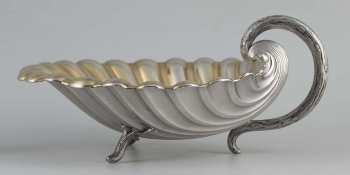 S/Mt/504/ML - Patera z uchwytem, w formie muszli przegrzebka ustawionej poziomo na  dwóch nóżkach - trzecią nóżkę tworzy zakończenie pionowo umocowanego esowatego ucha. 
Na odwrocie sygnatura segmentowa:
- znak miejski Petersburga
- znak imienny złotnika  