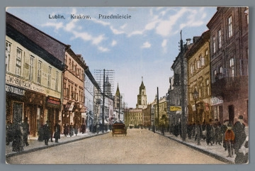 ML/H/3165 - Pocztówka kolorowa z widokiem na ulicę Krakowskie Przedmieście. Widok w kierunku Bramy Krakowskiej. Ujęcie w poziomie. Na pierwszym planie ulica w rozszerzonej perspektywie. Po obu stronach zabudowa kamienic z różnokolorowymi fasadami i szyldami w językach polskim i rosyjskim. Na chodnikach przechodnie. Na ulicy samochód. Rozstawione słupy telegraficzne. W oddali Wieża Trynitarska, fragment kościoła Św. Ducha i wieża Ratusza. W górnej partii jasne niebo z białymi obłokami. Wzdłuż górnej krawędzi napis informacyjny drukiem w kolorze czarnym. 
Na rewersie brązowa linatura. W miejscu adresowym wpisane nazwisko adresata, Joanny Mikiettówny. W miejscu na korespondencje odręczne pismo czarnym atramentem datowane na 2 sierpnia 1947 r. W korespondencji informacja o jej powstaniu w Lublinie i adresowaniu do Kazimierza. Brak śladu obiegu pocztowego. W l.d. rogu nadrukiem w kolorze brązowym data i seria wydawnicza. Pośrodku dolnej krawędzi nadruk z logo wydawcy w kolorze brązowym.

