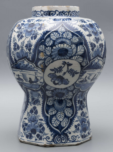 S/CS/1516/ML - Wazon balasowy z wysoka podstawą, wybrzuszonym korpusem i krótką szyją, ośmioboczny, o podziale zaznaczonym na całej wysokości. Czerep kremowy, szkliwo białe, dekoracja malowana podszkliwnie ciemnobłękitnym kobaltem. Na całej powierzchni regularnie rozmieszczony wzór lambrekinowy z motywami dużych kwiatów na błękitnym tle, przedzielony partiami białego tła z błękitnymi kwiatami. W dolnej części korpusu białe zezerwy z dekoracja naprzemienną: kwiatowa i figuralną – silnie uproszczone sylwetki ludzi w pejzażu. Na szyi fryz wolutowy.
 