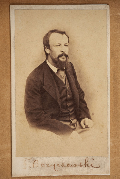 Tableau szklone zewnętrznie, w ramie, zawiera na tekturowym podłożu 15 fotografii uczestników powstania z terenu Wołynia. Pośrodku brak jednej, większej fotografii. Zdjęcia wykonane w sepii, w formacie pocztówkowym, niektóre z nich są podpisane pod spodem i na odwrociu: Eugeniusz Rdułtowski, Herkulan Kardussowski, F. Boryczewski, Antoni Straszewicz, Alfons Romanowski, Adam Hreczyna, Jan Grabis, Antoni Szymkiewicz.
Niektóre fotografie mają na kartonikach wyciskane napisy w języku rosyjskim. W środku tableau, pod pierwszym rzędem zdjęć przymocowany krzyżyk wykonany z chleba i tabaki, dekorowany motywem różyczek. Nad krzyżykiem druciana korona cierniowa, na niej krzyżyk z metalu z gałązką palmową. Niżej, pod brakującą fotografią lufka (?) z tektury, pierścionek i mały medalion ze Świętą Rodziną. Poniżej przymocowany grzebień rogowy, jakucki z napisem w języku rosyjskim i datą: 1864. Całość w ozdobnej ramie z dekoracyjnymi narożnikami, koroną, herbami Polski, Litwy, herbem z literą S. 