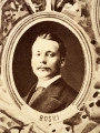 Fotografie w odcieniu sepii umieszczone na tle drzew i roślin, w centralnym miejscu postać kobiety ze sztandarem i aniołkami, wkomponowane widoki budowanej stacji, mostu kolejowego i lokomotywy. Największe zdjęcie w górnej, środkowej części bez podpisu, prawdopodobnie inż. głównej kolei nadwiślańskiej Tadeusz Chrzanowski lub jego następca Walery Titkow. Wśród podobizn pracownicy Biura Głównego Inżyniera: inż. Włodzimierz Stanisławski - pomocnik głównego inżyniera; inż. Feliks Kucharzewski -  pomocnik naczelnika biura; Feliks Kamocki - naczelnik kancelarii; Witold Lanci - naczelnik Wydz. Architektury; dr Wacław Lasocki- służba zdrowia; Władysław Radwan - sprawy zakupu gruntów; inż. Stanisław hr Scipio - projektant mostów kolejowych i jego współpracownicy: inż. Stefan Zieliński, inż. Maurycy Machalski, inż. Feliks Kucharzewski. Fotografia w passe - partout, za szkłem, oprawiona w drewnianą, profilowaną ramę.