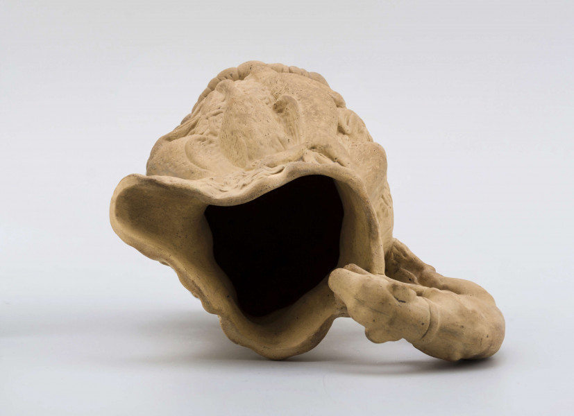 Dzbanek o kształcie zbliżonym do tralki na niskiej szerokiej stopie, z uchem; opracowany reliefowo sprawia wrażenie wydrążonego pnia drzewa, na którym zawieszone są upolowane ptaki i zwierzęta (m. in. bażanty, kaczki, zające, lis), ucho tworzy pełnoplastyczna figurka charta wspinającego się na wyciągniętych łapach i zaglądającego do środka. Powierzchnia matowa, bez polewy.
Na spodzie sygnatura odciśnięta w masie:
- Lubartów – kursywą
