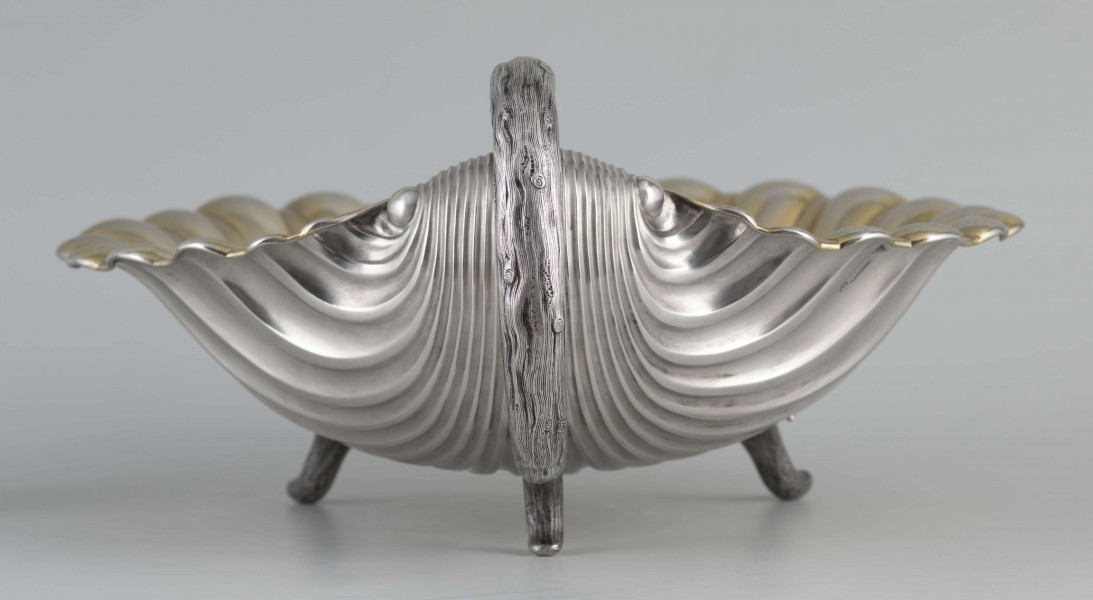 S/Mt/504/ML - Patera z uchwytem, w formie muszli przegrzebka ustawionej poziomo na  dwóch nóżkach - trzecią nóżkę tworzy zakończenie pionowo umocowanego esowatego ucha. 
Na odwrocie sygnatura segmentowa:
- znak miejski Petersburga
- znak imienny złotnika  