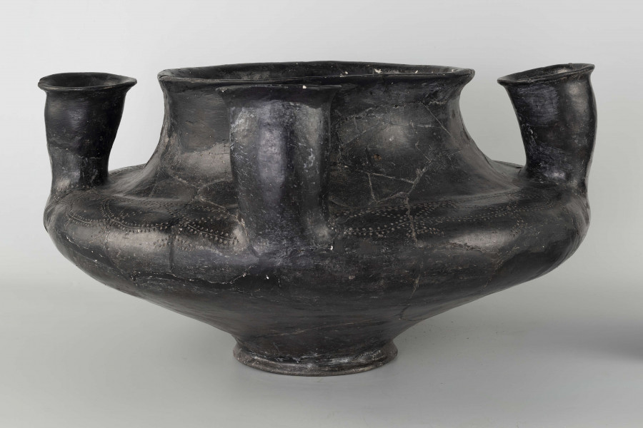 598/A/ML - naczynie kultowe (kernos) kultury pomorskiej; 
wymiary dodatkowe: 25,0 cm - średnica centralnego wylewu
opis: naczynie wazowate o czarnej, błyszczącej powierzchni, którego brzusiec został ozdobiony ornamentem złożonym z linii rytych oraz nakłuć; wokół głównego otworu posiada cztery symetrycznie rozmieszczone kielichy-rytony, które mają nieco wydęte ścianki boczne i kielichowato rozchylone na zewnątrz krawędzie otworów; rytony łączą się z głównym otworem kanalikami; 