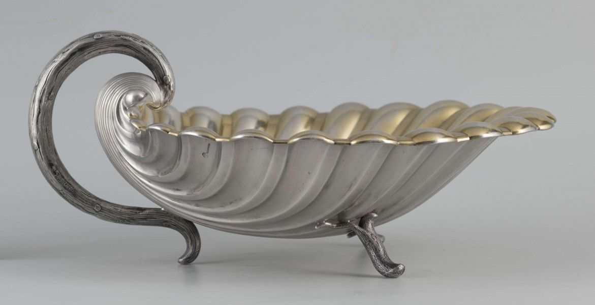 S/Mt/504/ML - Patera z uchwytem, w formie muszli przegrzebka ustawionej poziomo na  dwóch nóżkach - trzecią nóżkę tworzy zakończenie pionowo umocowanego esowatego ucha. 
Na odwrocie sygnatura segmentowa:
- znak miejski Petersburga
- znak imienny złotnika  