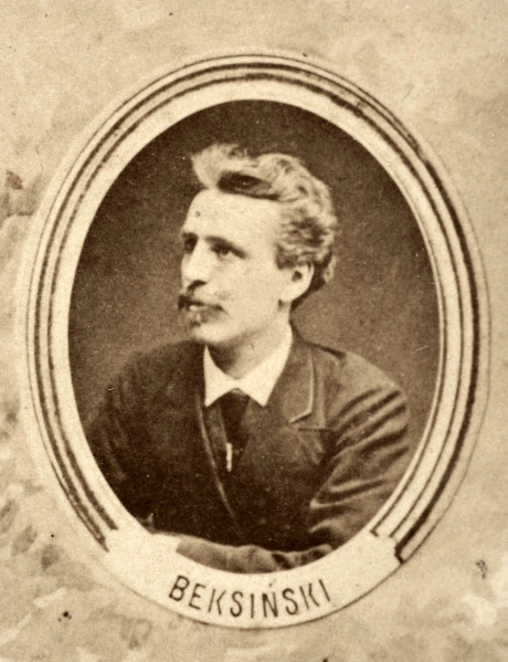 Fotografie w odcieniu sepii umieszczone na tle drzew i roślin, w centralnym miejscu postać kobiety ze sztandarem i aniołkami, wkomponowane widoki budowanej stacji, mostu kolejowego i lokomotywy. Największe zdjęcie w górnej, środkowej części bez podpisu, prawdopodobnie inż. głównej kolei nadwiślańskiej Tadeusz Chrzanowski lub jego następca Walery Titkow. Wśród podobizn pracownicy Biura Głównego Inżyniera: inż. Włodzimierz Stanisławski - pomocnik głównego inżyniera; inż. Feliks Kucharzewski -  pomocnik naczelnika biura; Feliks Kamocki - naczelnik kancelarii; Witold Lanci - naczelnik Wydz. Architektury; dr Wacław Lasocki- służba zdrowia; Władysław Radwan - sprawy zakupu gruntów; inż. Stanisław hr Scipio - projektant mostów kolejowych i jego współpracownicy: inż. Stefan Zieliński, inż. Maurycy Machalski, inż. Feliks Kucharzewski. Fotografia w passe - partout, za szkłem, oprawiona w drewnianą, profilowaną ramę.