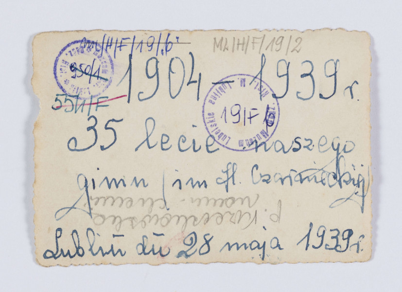 ML/H/F/19/2 - Na fotografii pozuje 16 dziewcząt - uczennic gimnazjum z trójką nauczycielek. Pośrodku stoi m.in. Irena Krzeczkowska. Dziewczęta ubrane sa w stroje ludowe: pasiaste spódnice, kamizelki, korale. Niektóre mają na głowach wianki z kwiatów. Stoją na chodniku przed budynkiem na tle czarnych, zakończonych łukiem drzwi. Dziewczęta w pierwszym rzędzie kucają.
Fotografia wykonana z okazji 35. lecia Gimnazjum H. Czarnieckiej w Lublinie.