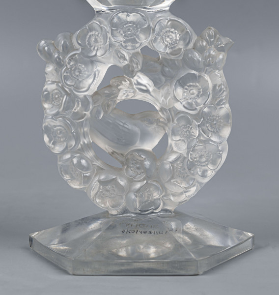 S/CS/1681/ML - Wazon w formie kielicha ze szkła bezbarwnego grubościennego; na sześciobocznej fasetowanej podstawie, trzon zdobiony plastycznie i matowiony w formie owalnego wieńca, wewnątrz którego siedzą dwa ptaszki - kolibry; czara koniczna fasetowana sześciobocznie z płaską krawędzią.
 