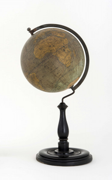 Globus bez tytułu, roku wydania i granic państwowych. Brak hipsometrii, powierzchnia kontynentów jest bladożółta za wyjątkiem białej Antarktydy. Na lądach naniesiono rzeki, pustynie i jeziora zaznaczono szrafurą. Największe góry oznaczono metodą kreskową (za pomocą 