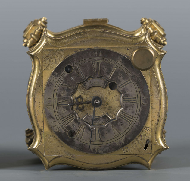 S/Mt/428/ML - Mechanizm o szkielecie płytowym, kwadratowym, łączonym balaskami. Wychwyt szpindlowy regulowany balansem włosowym; napęd sprężynowy chodu ze slimakiem wyrównawczym z funkcją bicia godzin i minut. Umieszczony w szkatule kwadratowej o falistych brzegach, na 4 nóżkach wolutowych; ścianki boczne oszklone w ozdobnie profilowanych ramkach, w narożach ornamenty muszlowo-wolutowe. W tarczy otwory naciągów przysłaniane, w narożniku wyłącznik biciawyłącznik bicia. Pierścień godzinowy srebrzony z rzymskimi oznaczeniemi godzin, arabskimi minut oraz kreskowa skala minutowa. Dwie proste wskazówki: godzinowa i minutowa. Na płycie dolnej mechanizmu obok koka, kółko regulacji chodu zegara: Avance Retard. Dwa młotki w formie muszli, dwie czasze zdwonków koncentrycznie umieszczone w klapie podstawy. 
Pośrodku tarczy dwie plakietki z dzieloną sygnaturą: 