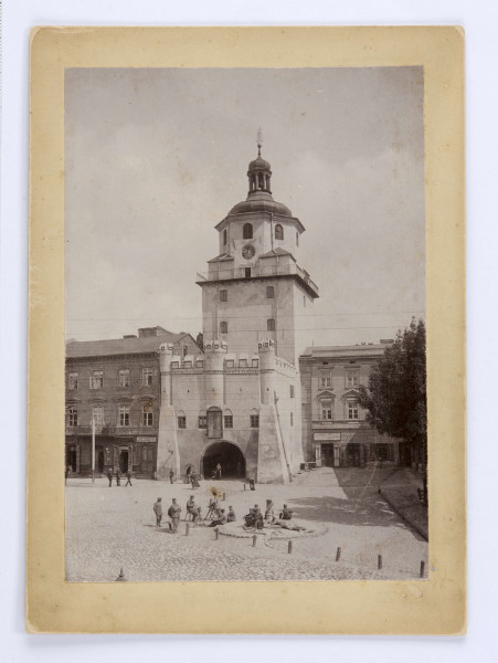 Brama Krakowska otynkowana, z balustradą żelazna dookoła wieży na wysokosci balkonu. Pod zegarem podwieszona informacja o temperaturze powietrza: 