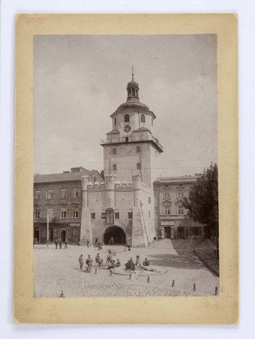 Brama Krakowska otynkowana, z balustradą żelazna dookoła wieży na wysokosci balkonu. Pod zegarem podwieszona informacja o temperaturze powietrza: 