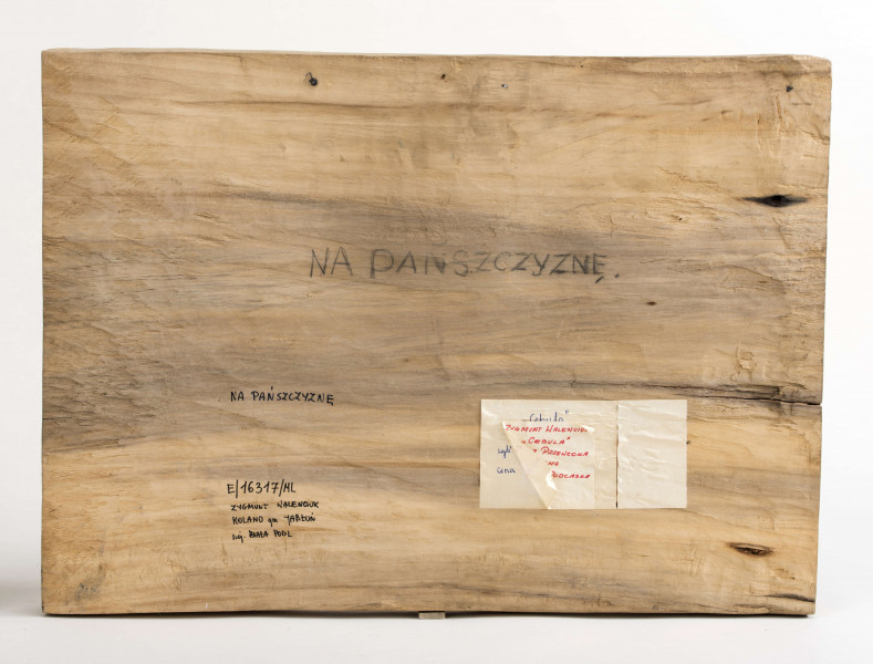 Płaskorzeźba z drewna lipowego, technika strugania, polichromowana przedstawiająca grupę kobiet i ekonoma. Centralnie zakomponowana została grupa kobiet, składająca się z 5 osób, idących drogą (droga niepolichromowana). Sylwetki trzech kobiet w całości, dwóch – widoczne tylko głowy. Kobiety z przodu są w sukienkach sięgających za kolana (kobieta z lewej ma w pasie przewiązany  fartuszek), białych chustkach na głowie i zawiązanych pod brodą, półbutach. Kobieta z prawej, w prawej ręce trzyma sierp, w lewek koszyczek. Kobieta w środku – w prawej ręce trzyma sierp. Kobieta  z lewej – sierp trzyma w lewej ręce. 
Z lewej strony płaskorzeźby zakomponowana postać ekonoma., w fioletowej kurtce przespanej pomarańczowym pasem, z przewieszona przez ramię torbą, w żółtawym kapeluszu z rondem, w brązowych spodniach wpuszczonych w buty z cholewami. Postać przedstawiona z tyłu, głowa z profilu. W prawej ręce, przez łokieć, wysunięty bat. W głębi z prawej strony ekonoma – sylwetki dwóch kobiet en face, z lewej – dwoje dzieci. 
Z prawej strony płaskorzeźby – pole, na którym w głębi widoczne są snopy zboża, z przodu – na polu za ogrodzeniem, postać chłopca w czerwonej szpiczastej czapce, czerwonej bluzie i niebieskich spodniach. W głębi na tle widoczne, z prawej strony,  dworek oraz dalej 3 chaty.