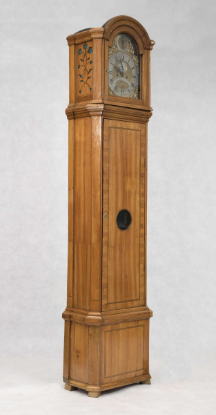 Tarcza w kształcie kwadratu zwieńczonego półkolem, złocona, w narożach ornamenty odlewane z brązu, złocone; pierścień  godzinowy srebrzony z rzymskimi oznaczeniami godzin i zaznaczonymi minutami, wewnątrz tarcza sekundnika, tarczka budzika, plakietka z sygnaturą 