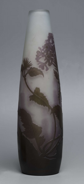 S/CS/1620/ML - Wazon o kształcie wrzecionowatym ze szkła grubościennego, matowego, bezbarwnego,  podbarwionego od dołu fioletem, od góry błękitem. Powlekany warstwą liliową i brązowooliwkową; w niej trawiona i polerowana dekoracja roślinna: swobodnie rozmieszczone gałązki werbeny z kwiatami.
 