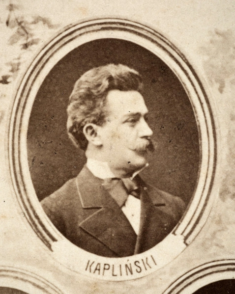 Fotografie w odcieniu sepii umieszczone na tle drzew i roślin, w centralnym miejscu postać kobiety ze sztandarem i aniołkami, wkomponowane widoki budowanej stacji, mostu kolejowego i lokomotywy. Największe zdjęcie w górnej, środkowej części bez podpisu, prawdopodobnie inż. głównej kolei nadwiślańskiej Tadeusz Chrzanowski lub jego następca Walery Titkow. Wśród podobizn pracownicy Biura Głównego Inżyniera: inż. Włodzimierz Stanisławski - pomocnik głównego inżyniera; inż. Feliks Kucharzewski -  pomocnik naczelnika biura; Feliks Kamocki - naczelnik kancelarii; Witold Lanci - naczelnik Wydz. Architektury; dr Wacław Lasocki- służba zdrowia; Władysław Radwan - sprawy zakupu gruntów; inż. Stanisław hr Scipio - projektant mostów kolejowych i jego współpracownicy: inż. Stefan Zieliński, inż. Maurycy Machalski, inż. Feliks Kucharzewski. Fotografia w passe - partout, za szkłem, oprawiona w drewnianą, profilowaną ramę.