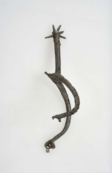 Ostroga żelazna w kształcie wideł z półkoliście wygiętymi ramionami zakaończonymi gwiazdkami; kolec również zakończony gwiazdką umocowaną przez włożenie jej w rozszczepiony kolec i przewleczono nitem