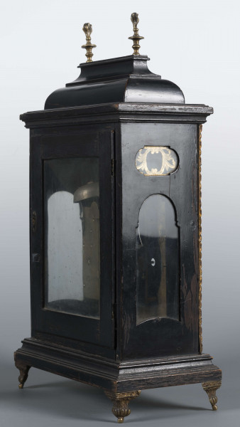 S/Mt/531/ML - Obudowa szafkowa, czworoboczna ze schodkowym zwieńczeniem, pokryta czarną politurą, oszklona z czterech stron, na czterech nóżkach z mosiądzu; w górnych narożnikach mosiężne sterczyny w formie płonących wazonów. Mechanizm chodu i bicia o napędzie sprężynowym, z wahadłem i dwoma dzwonkami; bicie godzin i kwadransów, budzik i repetier. Tarcza biało emaliowana z czarnymi cyframi arabskimi godzin i minut, w niej trzy otwory na osie sprężyn; trzy wskazówki, godzinowa i minutowa - ozdobne, sekundowa prosta. W górnej części tarczy sygnatura pisana ozdobną kursywą: M.G. / Jurkiewicz /  w Lublinie. Powyżej tarczy wycięcie z widocznym wahadełkiem kontrolnym i trzy mniejsze emaliowane tarcze: środkowa z miniaturą pejzażową, boczne z wyłączeniem chodu i bicia.