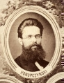 Fotografie w odcieniu sepii umieszczone na tle drzew i roślin, w centralnym miejscu postać kobiety ze sztandarem i aniołkami, wkomponowane widoki budowanej stacji, mostu kolejowego i lokomotywy. Największe zdjęcie w górnej, środkowej części bez podpisu, prawdopodobnie inż. głównej kolei nadwiślańskiej Tadeusz Chrzanowski lub jego następca Walery Titkow. Wśród podobizn pracownicy Biura Głównego Inżyniera: inż. Włodzimierz Stanisławski - pomocnik głównego inżyniera; inż. Feliks Kucharzewski -  pomocnik naczelnika biura; Feliks Kamocki - naczelnik kancelarii; Witold Lanci - naczelnik Wydz. Architektury; dr Wacław Lasocki- służba zdrowia; Władysław Radwan - sprawy zakupu gruntów; inż. Stanisław hr Scipio - projektant mostów kolejowych i jego współpracownicy: inż. Stefan Zieliński, inż. Maurycy Machalski, inż. Feliks Kucharzewski. Fotografia w passe - partout, za szkłem, oprawiona w drewnianą, profilowaną ramę.