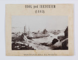 ML/H/F/75 - Zdjęcie ukazuje krajobraz Usola z zabudowaniami mieszkalnymi i gospodarczymi. Na pierwszym planie brzeg rzeki, na nim kopiec piachu. Zza kopca wyłania się statek. Po lewej płotek i fragment domu z bala. W oddali budynki mieszkalne i gospodarcze. Forografia naklejona na passepartout. W górnej części napis: 