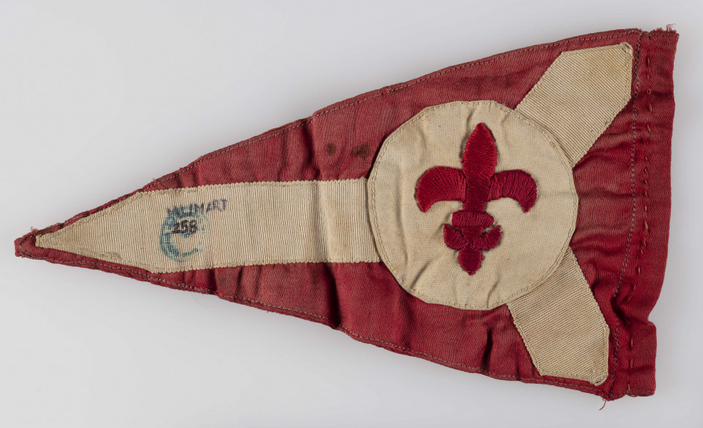 ML/MART/258 - Proporzec harcerski Oddziału AK Szarych Szeregów biorących udział w Powstaniu Warszawskim. Proporzec znaleziony przy Włodzimierzu Kadurze poległym w 1 dniach Powstania Warszawskiego w sierpniu 1944 roku. Proporzec w kształcie trójkąta, czerwony kolor z białymi wstawkami, na środku białe koło z wyhaftowaną czerwoną lilijka harcerską.