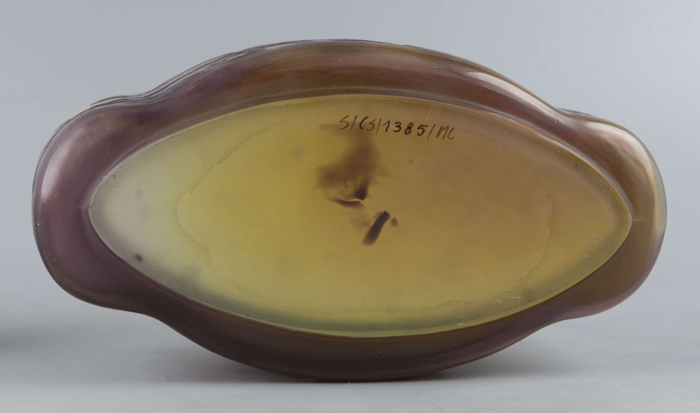 S/CS/1385/ML - Żardiniera ze szkła grubościennego, bezbarwnego, matowanego, podbarwianego żółtym i liliowym pudrem; na niskiej spiczasto-owalnej podstawie korpus o ściankach pionowo sfalowanych, u dołu lekko zaokrąglony, górna krawędź ścięta. Korpus pokryty warstwą liliową, w niej trawiony wzór roslinny: gałązka fuksji z kwiatami, przy dnie dookoła  pasmo liliowe o nieregularnym wykroju.
 