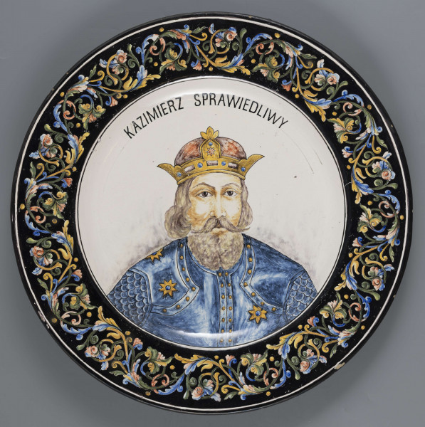 S/CS/1213/ML - Pólmisek pokrągły, gładki, szkliwiony, dekoracja malowana wielobarwnie. W lustrze malowane popiersie króla w koronie zamkniętej i zbroi, nad głową napis majuskułą w czarnym kolorze: KAZIMIERZ SPRAWIEDLIWY. Na kołnierzu fryz z liściasto-wolutowej girlandy, wilobarwnej, na ciemnobłękitnym tle.   
