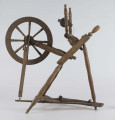 E/16647/ML - Kołowrotek poziomy, drewniany, ozdobnie toczony. Drewno niemalowane. Podstawa to 3 skośnie ustawione nóżki. Dwie z nich osadzone w wąskiej listwie. Górne końce nóżek osadzone w prostokątnej pochyłej grubej desce (11 x 32 x 4 cm). Stanowi ona podstawę do osadzenia koła napędowego i szpuli zwijającej nici. W niej zamocowany uchwyt połączony ze śrubą, która reguluje położenie szpuli. Koło osadzone na metalowej ośce posiada 8 toczonych ozdobnie szprych. Jeden koniec ośki połączony pionową ruchomą listewką z pedałem wprawiającym w ruch kołowrotek. Szpula osadzona również na metalowej ośce.