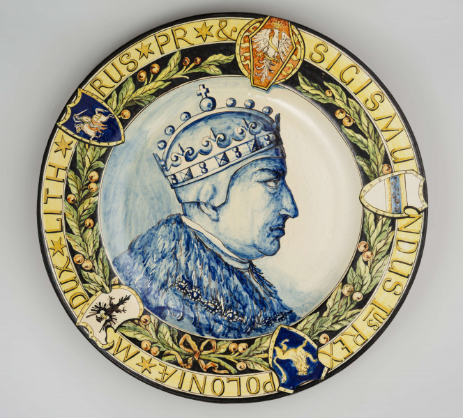 Pólmisek pokrągły, gładki, szkliwiony, dekoracja malowana wielobarwnie. W lustrze malowane błękitem kobaltowym popiersie portretowe Zygmunta I w profilu zwróconym w prawo. Kołnierz podzielony na dwa pasy: od środka zielona girlanda lauru z owocami przewiązana wstążką, na ciemnogranatowym tle; po zewnętrznej  na jasnożółtym tle cieniejsze konturowane litery majuskułowe tworzą napis: SIGISMUN/DUS Ius REX / POLONIAE * M /DUX * LITH */ RUS * PR * &. Pasy dekoracji przedziela pięć herbów regularnie rozmieszczonych: Orzeł, herb Habsburgów, herb Rusi, herb Prus i litewska Pogoń - wszystkie w ozdobnych renesansowych kartuszach. Krawędź obwiedziona ciemnogranatowym konturem.
