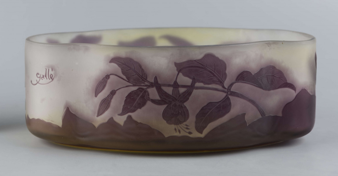 S/CS/1385/ML - Żardiniera ze szkła grubościennego, bezbarwnego, matowanego, podbarwianego żółtym i liliowym pudrem; na niskiej spiczasto-owalnej podstawie korpus o ściankach pionowo sfalowanych, u dołu lekko zaokrąglony, górna krawędź ścięta. Korpus pokryty warstwą liliową, w niej trawiony wzór roslinny: gałązka fuksji z kwiatami, przy dnie dookoła  pasmo liliowe o nieregularnym wykroju.
 