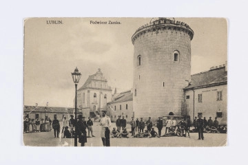 ML/H/2243 ML/H/2243 - Pocztówka czarnobiała z widokiem na dziedziniec zamku lubelskiego z czasów funkcjonowania więzienia. Widoczna grupa więźniów (kobiet i mężczyzn) oraz służby więziennej. Część osób stoi. Niektórzy siedzą na ziemi. Po lewej stojące rzędem kobiety. Na pierwszym planie naczelnik (?) w długiej białej dwurzędowej kurtce od munduru z epoletami oraz czapką z daszkiem i znaczkiem na otoku. Prawa ręka wsunięta za rozpiętą kurtkę, lewa w kieszeni ciemnych spodni. Obok niego stoi mężczyzna w czarnym płaszczu i kapeluszu z laską, oparty o latarnię zwieńczoną przeszklonym kloszem. Za postaciami widoczne zabudowania wzgórza zamkowego: dwukondygnacyjne skrzydło południowe z donżonem i Kaplicą Trójcy Świętej z balustradowym wejściem z poziomu dziedzińca oraz parterowy budynek zamykający dziedziniec od wschodu. Budowle otynkowane. Wieża z charakterystycznym boniowaniem. Na ścianach niższych budynków napisy w języku rosyjskim (m. in. kaplica prawosławna). Wzdłuż górnej krawędzi nadruk w kolorze czarnym z tytułem.
Na rewersie czarna linatura. Wzdłuż górnej krawędzi drukiem nazwa karty pocztowej w językach francuskim, polskim i rosyjskim. W l.g. rogu odbitka stemplem w kolorze fioletowym w numerem serii wydawniczej. Wzdłuż prawej krawędzi drukiem w kolorze czarnym nazwa nakładcy. Brak śladu obiegu pocztowego.
