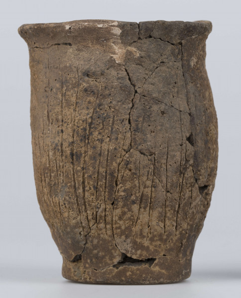 409/A/ML/2 - Naczynie esowate dno płaskie wyraźnie oddzielone brzusiec workowaty szyjka rozchylona pow zewnetrzna przy dnie i wylewie gładzona reszta obmazywana na brzuścu wykonano ostrym narzedziem nieregularne pionowe kreski