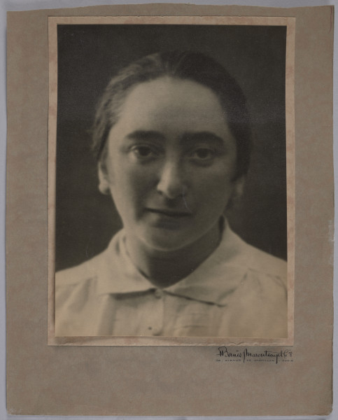 Fotografia studyjna Giny (Reginy) z Pinkusów Szwarc (1895–1973) vel Eugenii Markowej, naklejona na kartę przymocowaną do tektury, wykonana przed 1939 r. Czarno-białe zdjęcie młodej kobiety w ujęciu popiersia. Włosy upięte gładko, związane z tyłu, pozuje bez makijażu i biżuterii, w białej, zapinanej na guziki koszuli. Karton do którego przytwierdzona jest fotografia z faksymilą podpisu twórcy: 