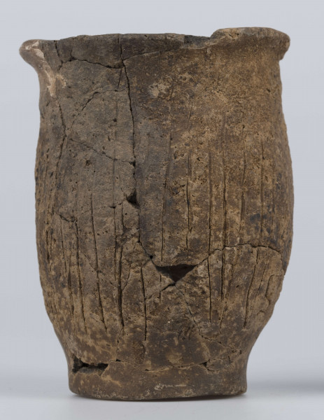 409/A/ML/2 - Naczynie esowate dno płaskie wyraźnie oddzielone brzusiec workowaty szyjka rozchylona pow zewnetrzna przy dnie i wylewie gładzona reszta obmazywana na brzuścu wykonano ostrym narzedziem nieregularne pionowe kreski