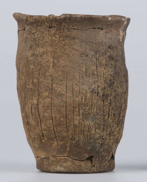 409/A/ML/2 - Naczynie esowate dno płaskie wyraźnie oddzielone brzusiec workowaty szyjka rozchylona pow zewnetrzna przy dnie i wylewie gładzona reszta obmazywana na brzuścu wykonano ostrym narzedziem nieregularne pionowe kreski