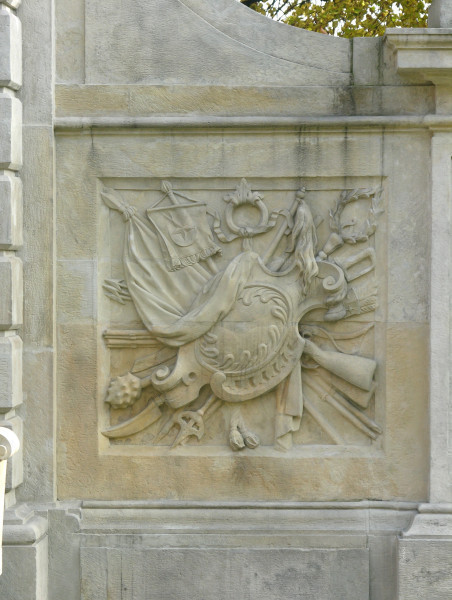 Płycina dekoracyjna na przyporze filaru - kompozycja składająca się z panoplii. Przykryte tarczą kartusza motywy militarne: buńczuk, sztandar z półksiężycem i pięcioramienną gwiazdą, szabla, łuk, strzelby, włócznie, kosy, halabardy, maczuga, strzały.