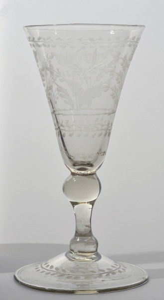 strona pierwsza. Koniczna czara rozszerza się ku wylewowi. Zdobi ją szeroki pas dekoracji roślinnej. Niżej tralkowata nóżka, łącząca czaszę ze stopą. Na stopie linearny otok z drobnymi, owalnymi, skośnie umieszczonymi po obu stronach otoku listkami.