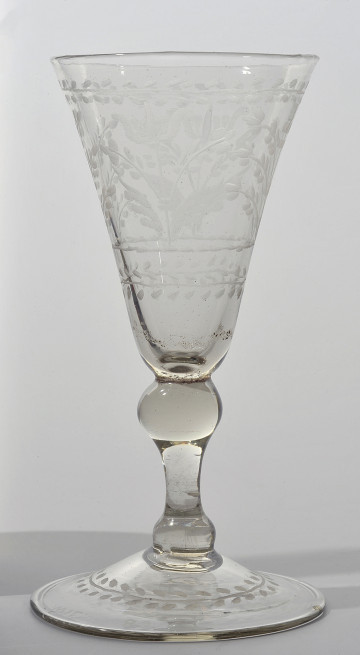 strona pierwsza. Koniczna czara rozszerza się ku wylewowi. Zdobi ją szeroki pas dekoracji roślinnej. Niżej tralkowata nóżka, łącząca czaszę ze stopą. Na stopie linearny otok z drobnymi, owalnymi, skośnie umieszczonymi po obu stronach otoku listkami.