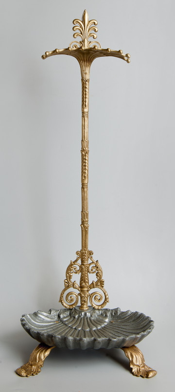 Ujęcie z przodu. Na dole widoczna podstawka w kształcie muszli. Pod podstawką widoczne są dwie wygięte stopki w motywie roślinnym. Przez tył podstawy przechodzi trzpień pokryty płaskorzeźbami. W dolnej partii, zwoje z wici akantowej. U góry trzpień przechodzi w płaską sterczynę. Poniżej sterczyny podpórka na przybory.