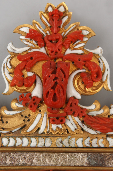 detal. Górna cześć kropielnicy palmeta biało złota z dekoracją koralową w formie elementów roślinnych.